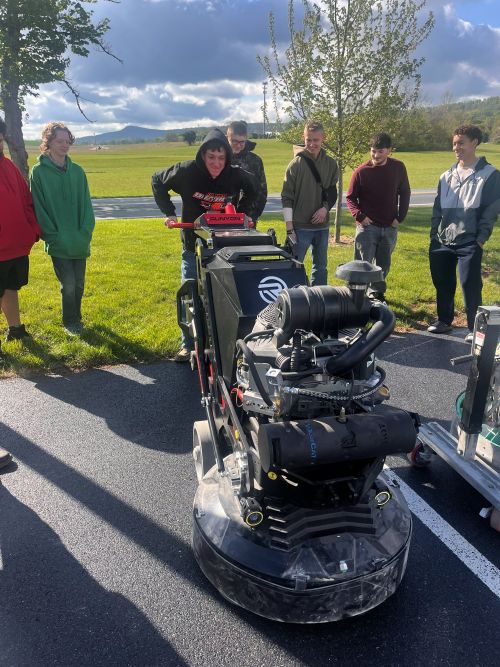 Student using a floor grinder during a career presentation by Durable Surfaces