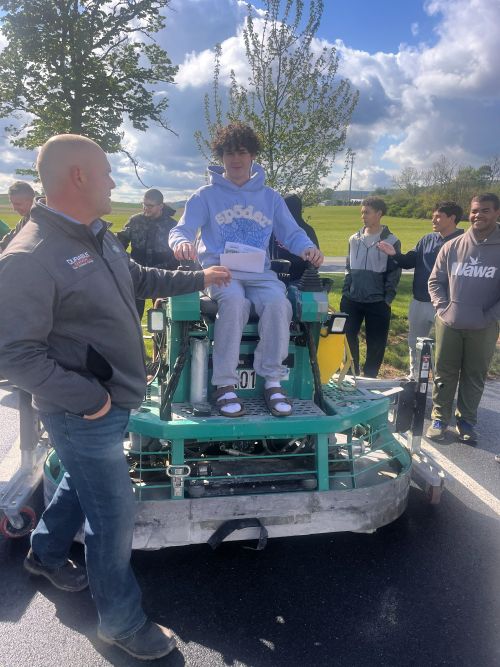 Student using a floor shaver during a career presentation by Durable Surfaces
